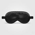 Black silk sleep mask with eye cups on a light gray background