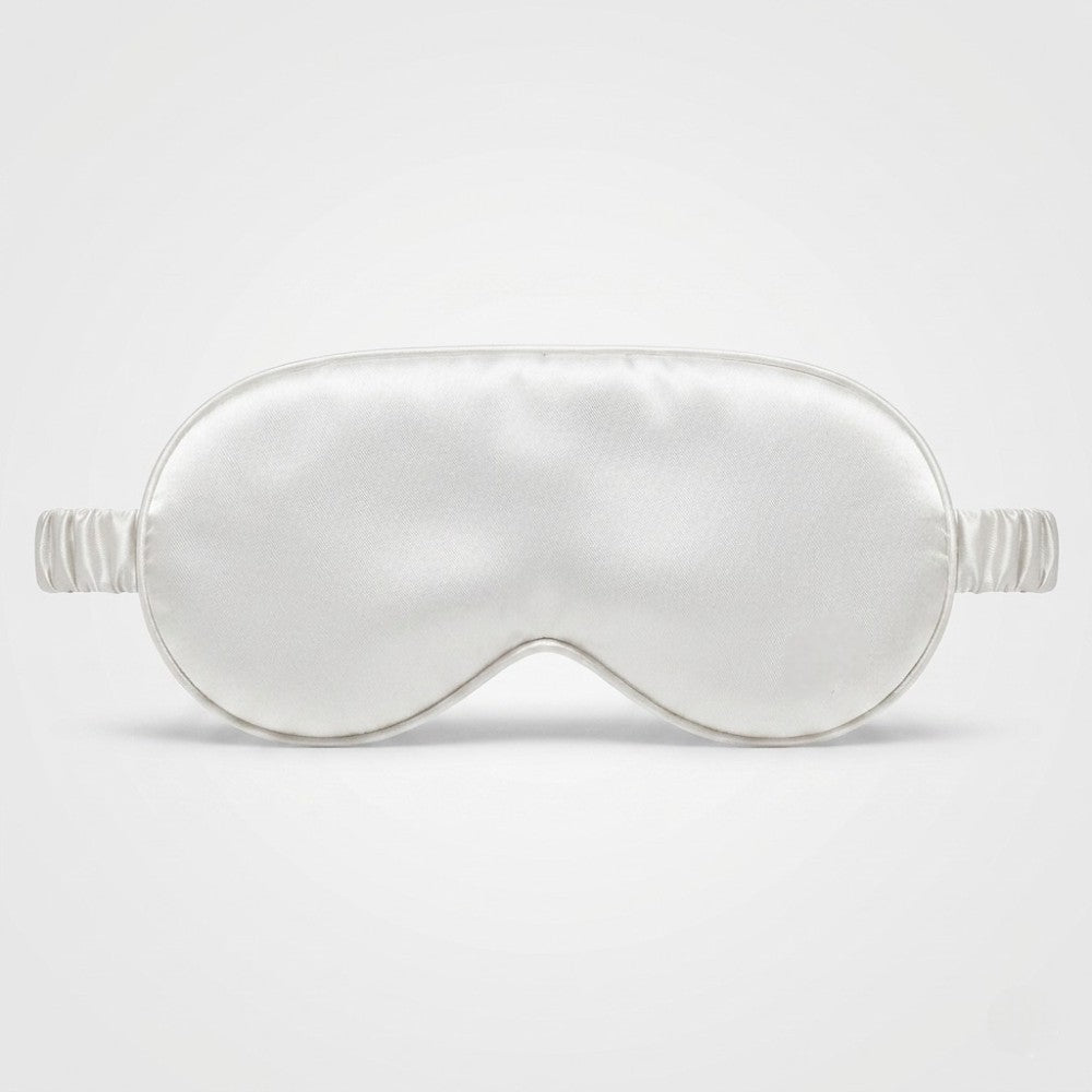 Ivory white silk sleep mask on a light gray background