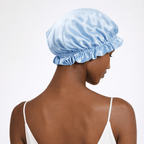 Back view of black woman wearing a blue silk bonnet on a white background