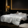 Bed with white silk duvet cover in a dimly lit bedroom