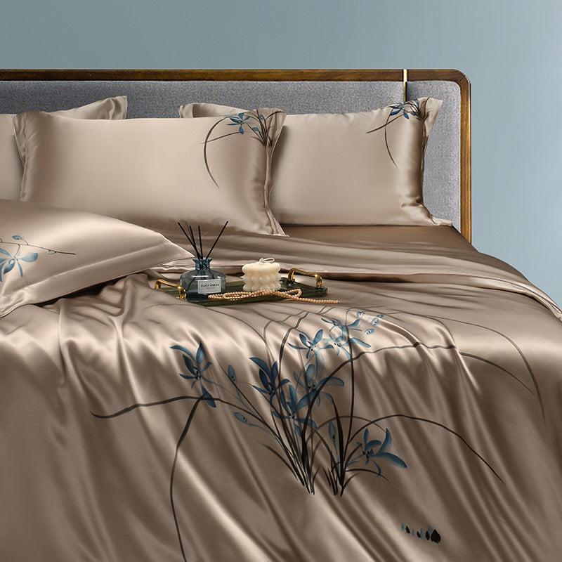 Beige silk bedspread with floral patterns on a bed against a light blue wall.