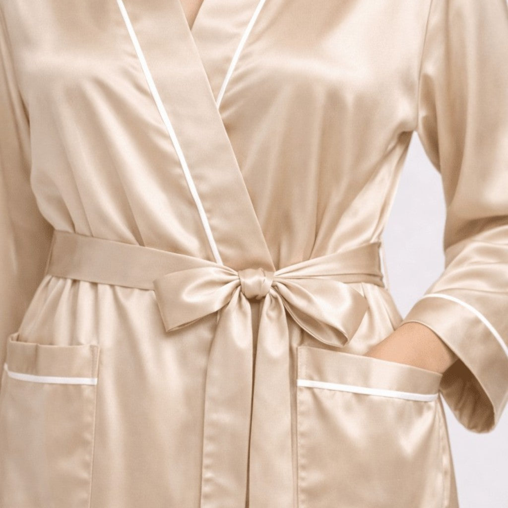 Champagne gold silk robe with white piping on a neutral background
