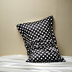 Black pillowcase with white polka dots on a beige background