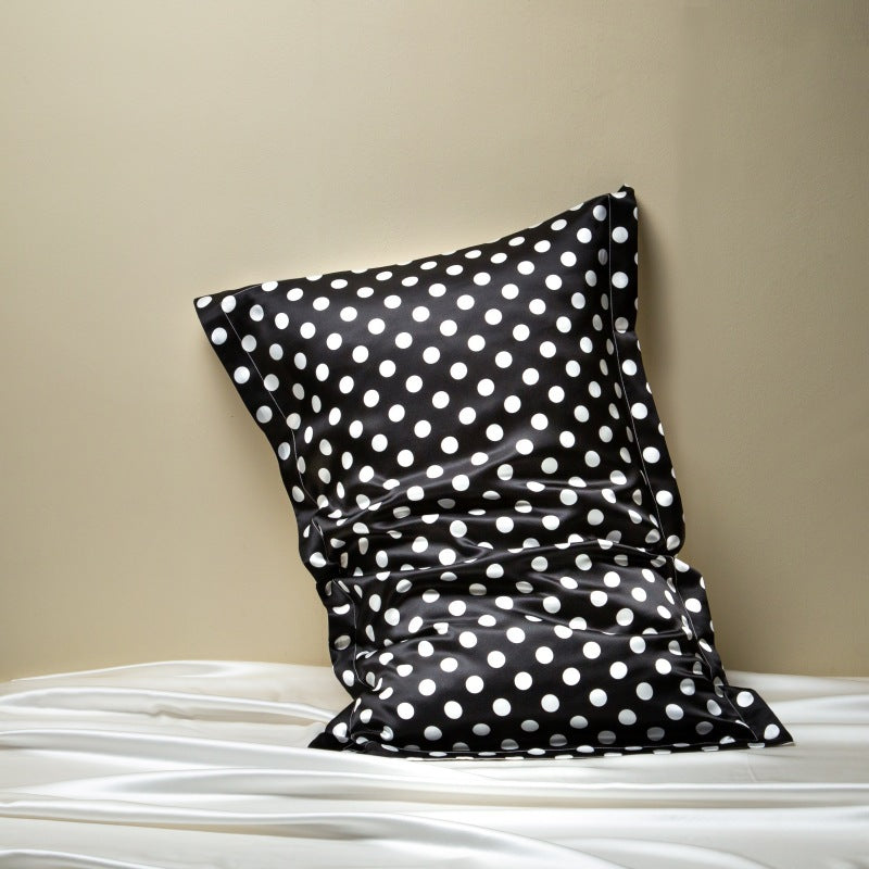 Black pillowcase with white polka dots on a beige background