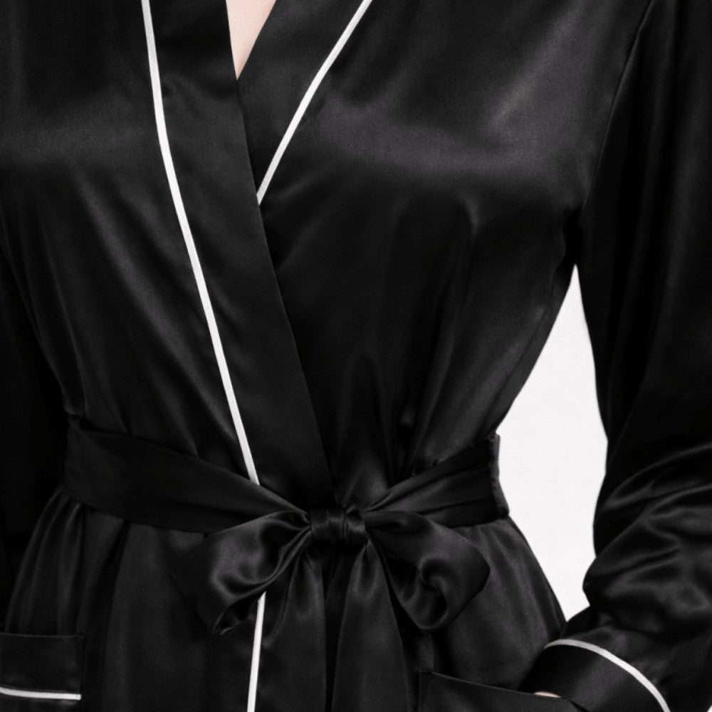 Black silk robe with white piping on a neutral background