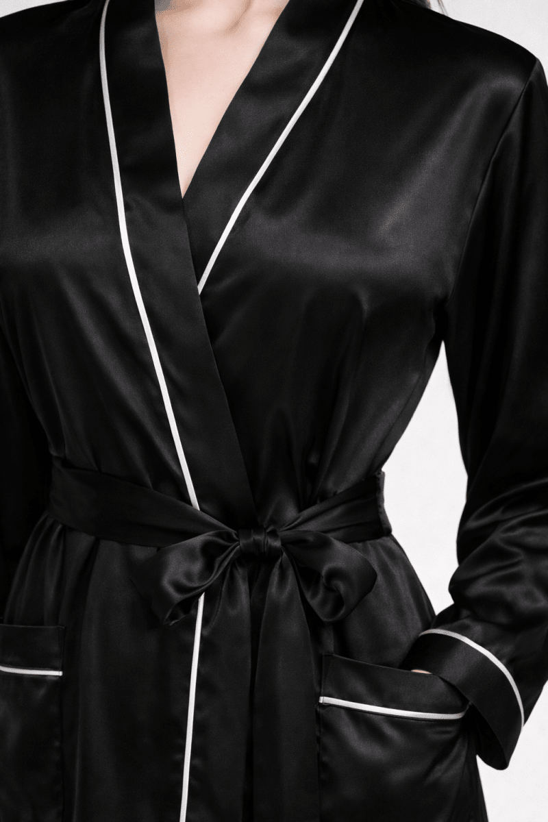 Black silk robe with white piping on a neutral background