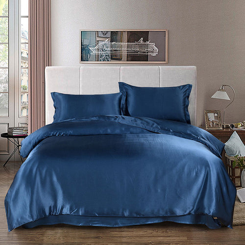 100% Mulberry silk duvet cover on a bed in a bedroom with a lamp and decor items.