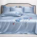 Blue silk floral bedspread set on a bed with matching pillows.