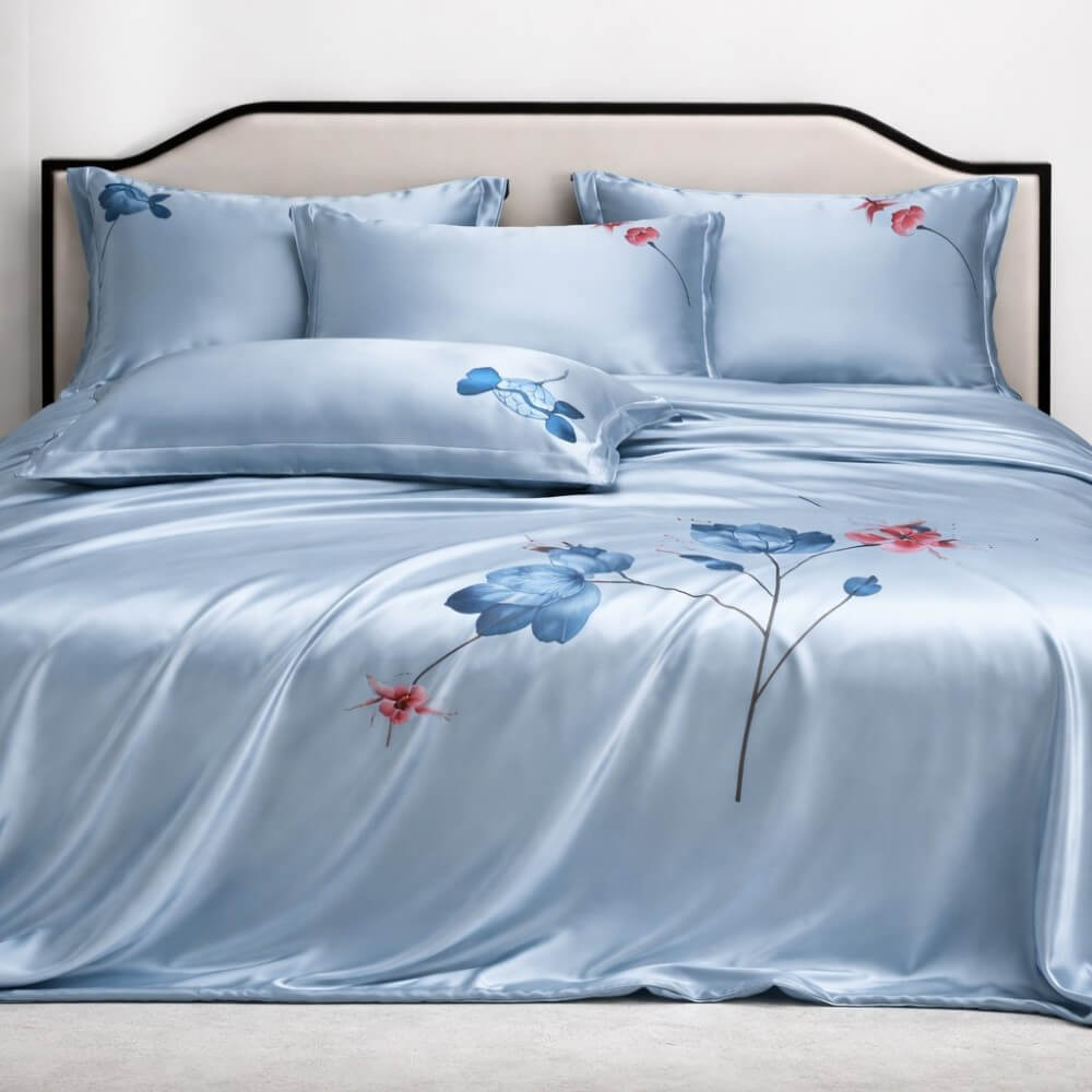 Blue silk floral bedspread set on a bed with matching pillows.