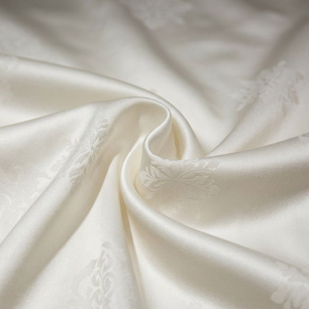 Close-up of textured cream silk fabric with subtle patterns