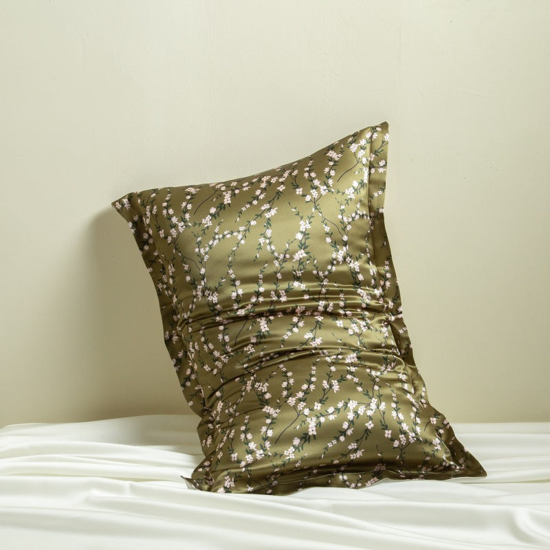 Decorative silk pillowcase with cherry blossom floral pattern on a white surface against a beige background