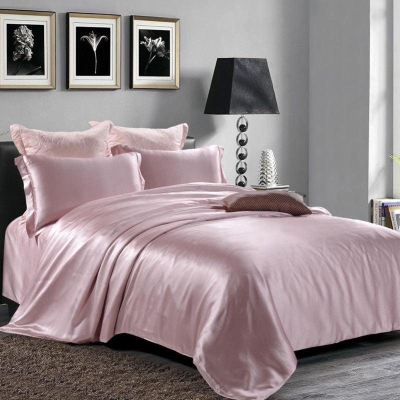 Elegant purple silk duvet cover on a bed in a bedroom with framed artwork and a lamp.