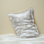 Floral-patterned silk pillowcase on a bed against a beige wall