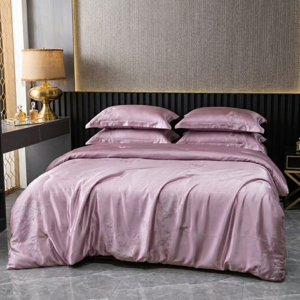Light purple silk bedding set on a bed in a bedroom with a lamp and nightstand.