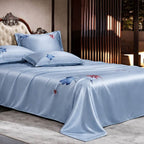 Light blue silk floral bedspread on a bed with matching pillows in a bedroom setting.