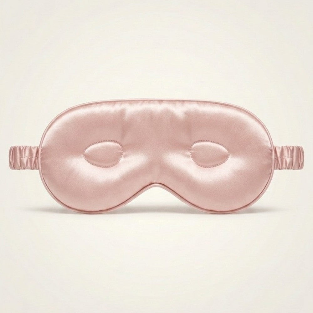 Pink silk sleep mask on a light beige background