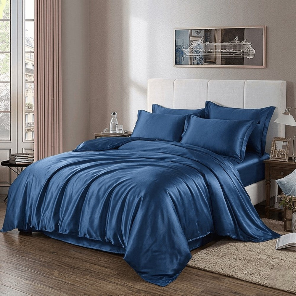 Navy blue silk duvet cover on a bed in a bedroom with a lamp and decor items.