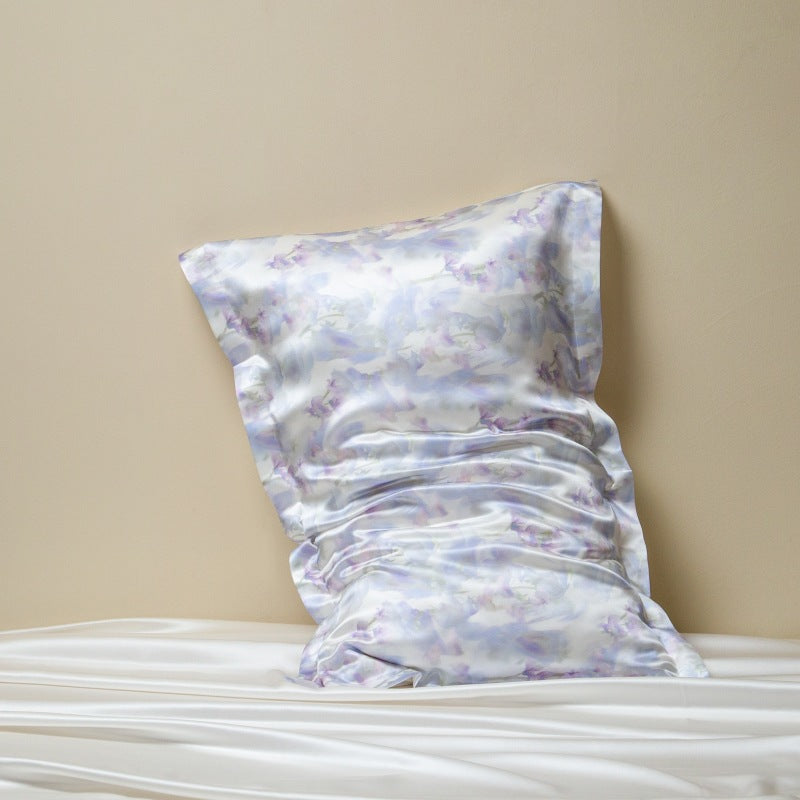 Pastel floral patterned silk pillow cover on a bed against a beige wall