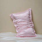 Pink houndstooth silk pillowcase on a white bed against a beige wall