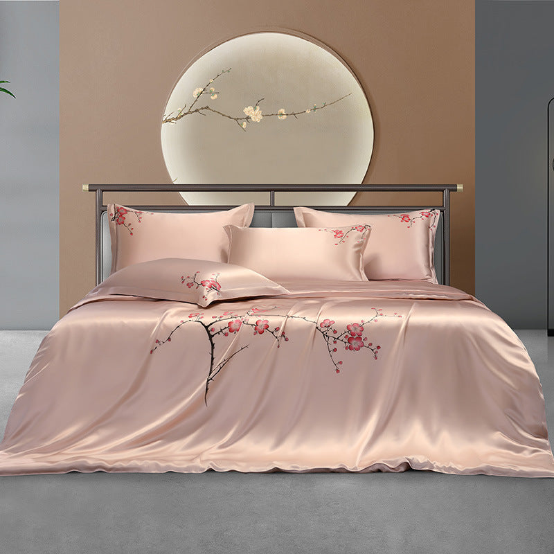 Pink silk floral bedding set on a bed with a decorative headboard in the background.