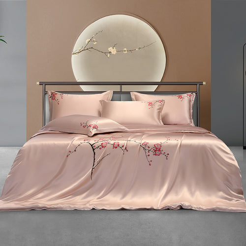 Pink silk floral bedding set on a bed with a decorative headboard in the background.