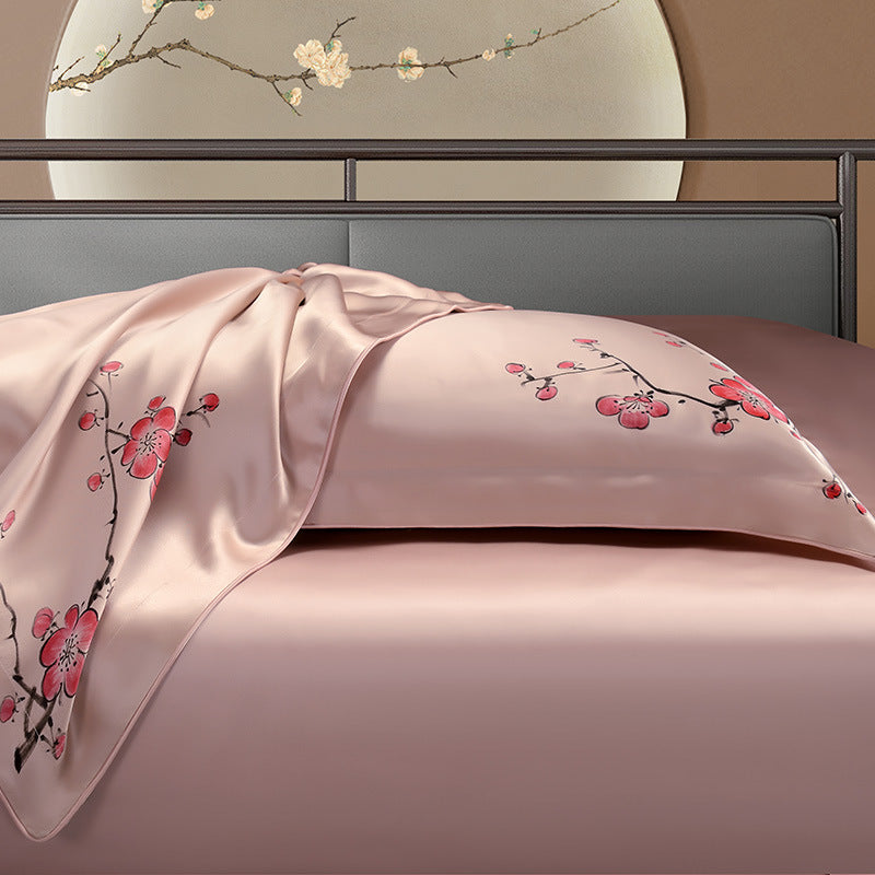 Pink silk floral embroidered bedding on a bed with a decorative headboard.