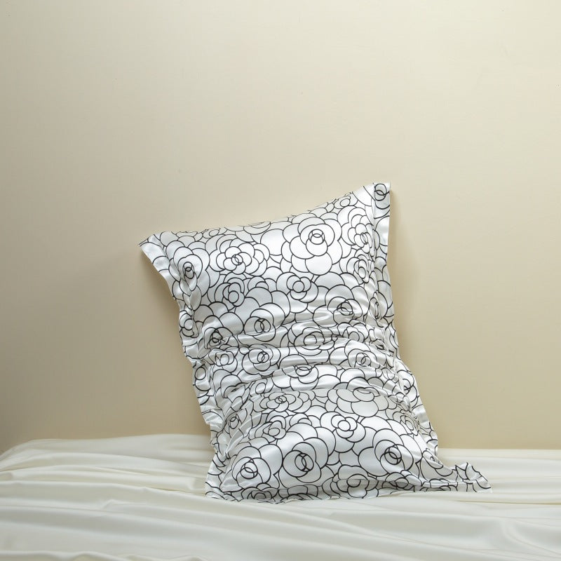 Rose petal floral patterned silk pillowcase on a pillow against a beige wall