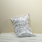 Rose petal floral patterned silk pillowcase on a pillow against a beige wall