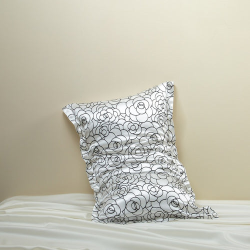 Rose petal floral patterned silk pillowcase on a pillow against a beige wall