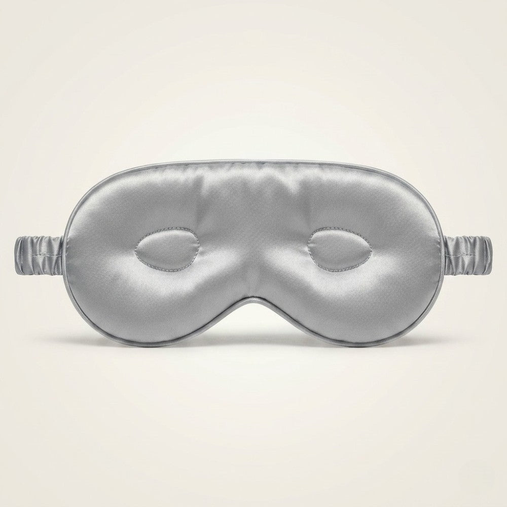Silver silk sleep mask on a beige background