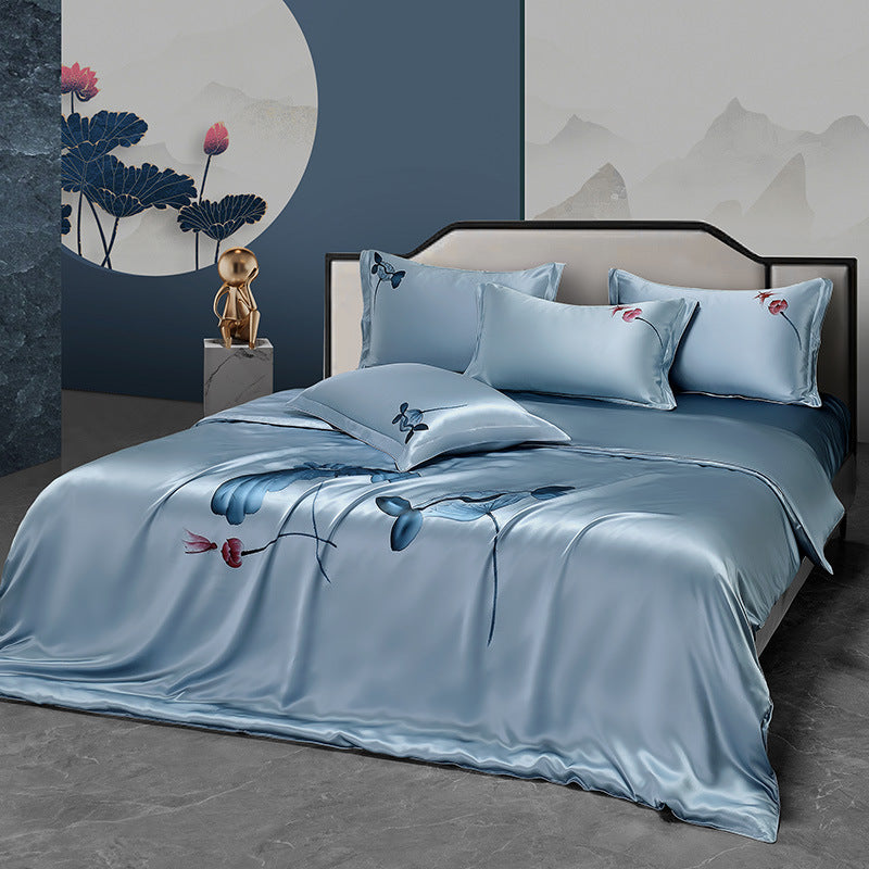 Blue silk bedding set on a bed with floral design in a bedroom setting.