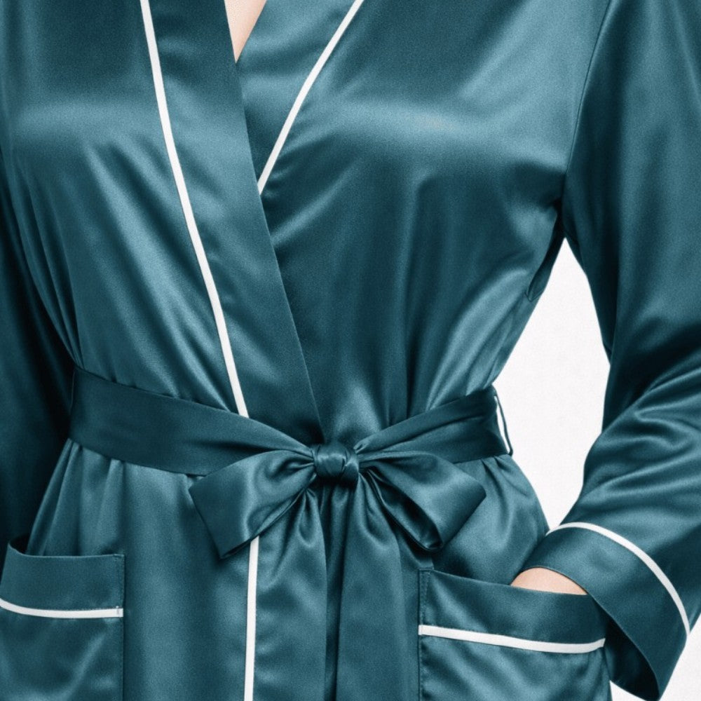 Teal silk robe with white piping on a light gray background