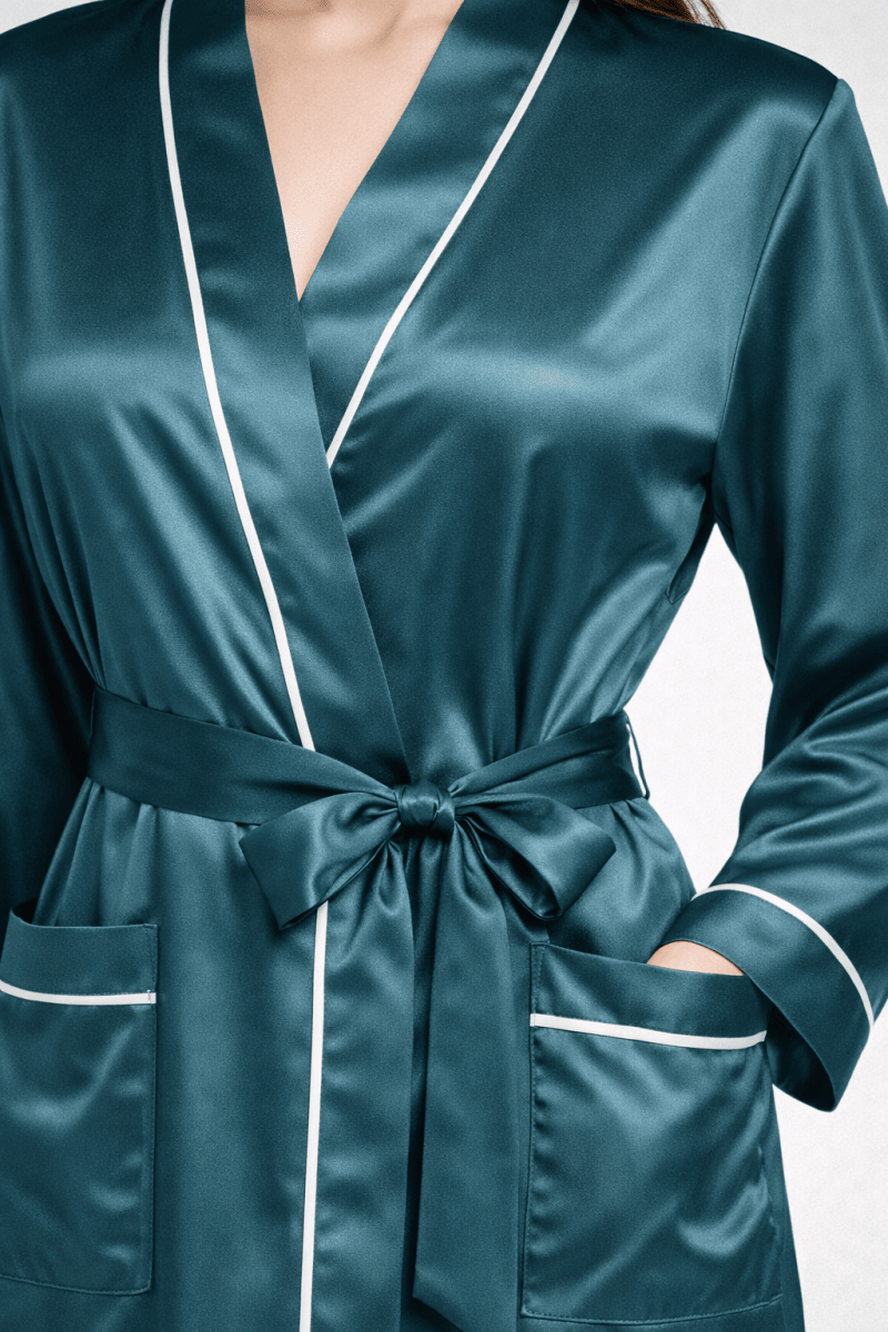 Teal silk robe with white piping on a neutral background