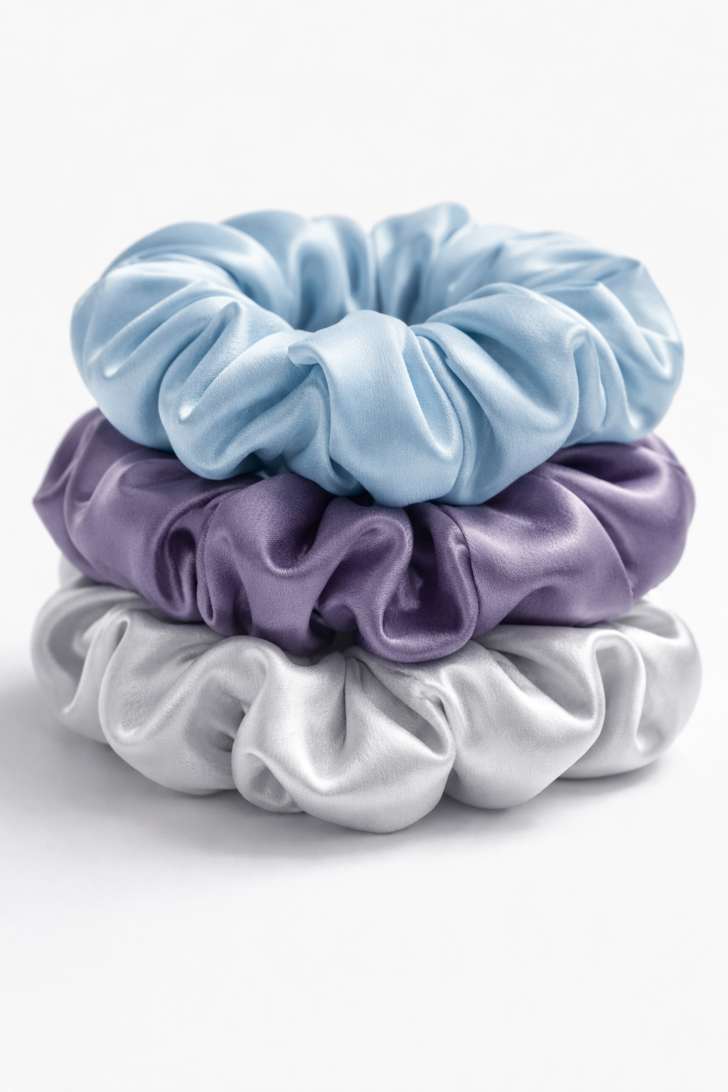 Three scrunchies in blue, purple, and white on a white background