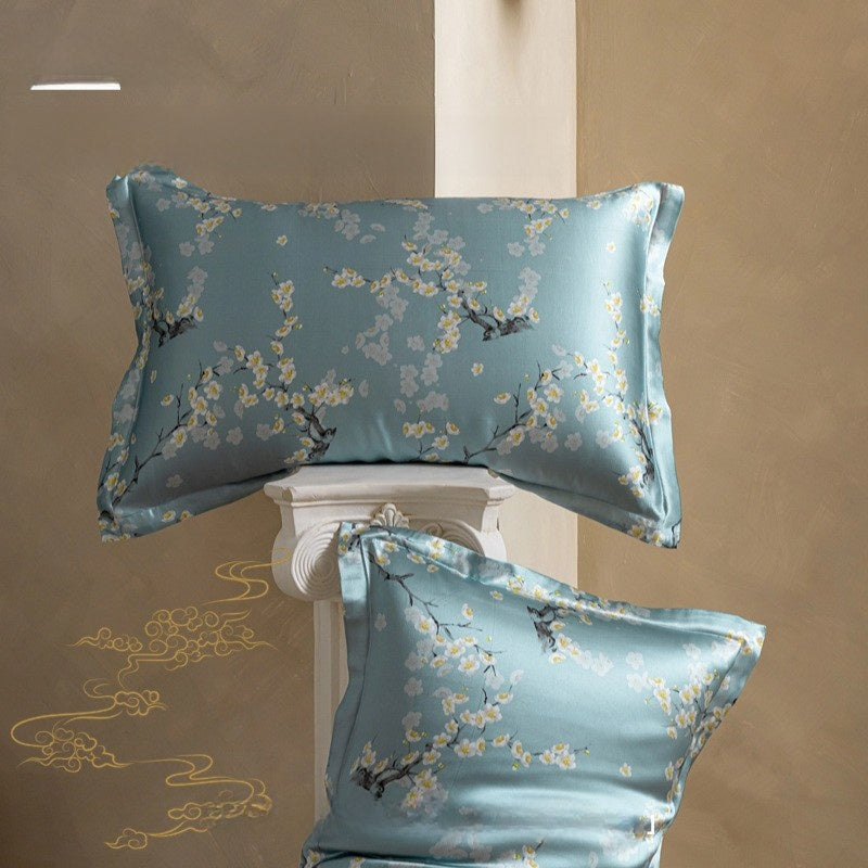 Two blue floral silk pillowcases on a decorative stand against a beige wall.