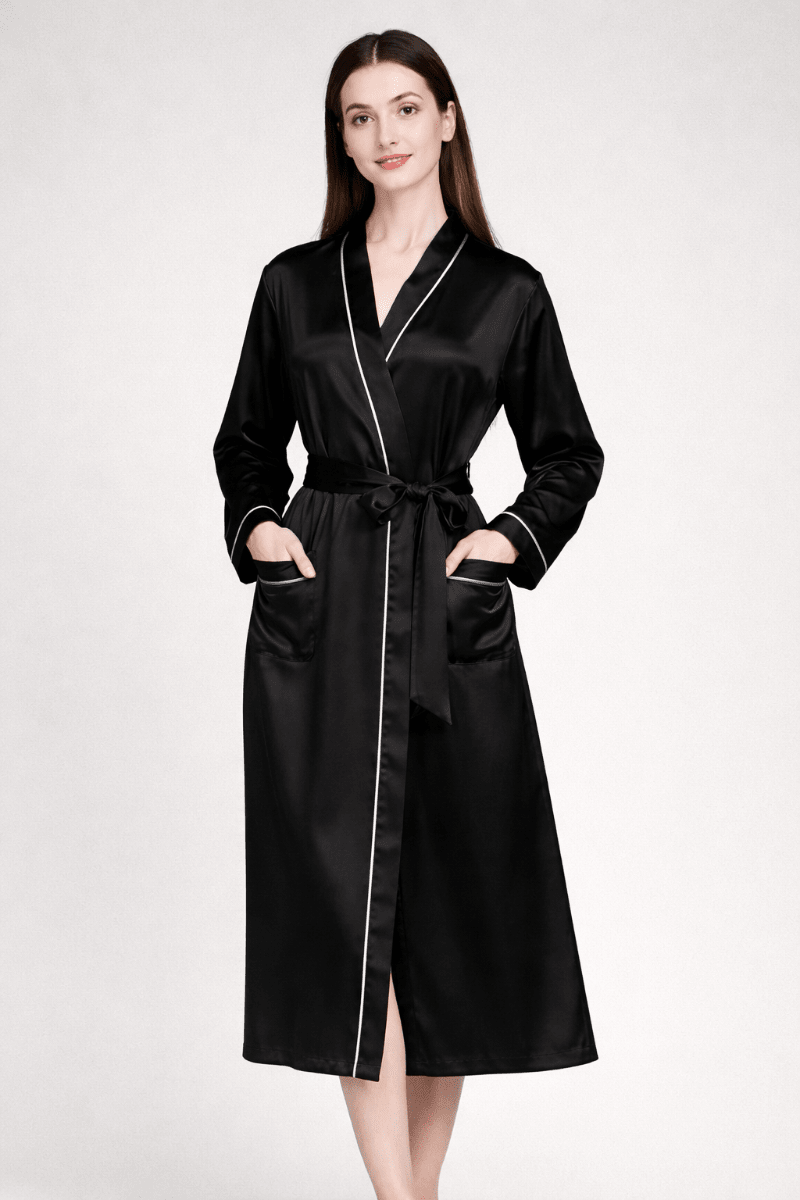 Woman wearing a black silk robe with white piping on a white background