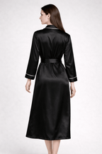 Woman wearing a black silk robe with white trim on a white background