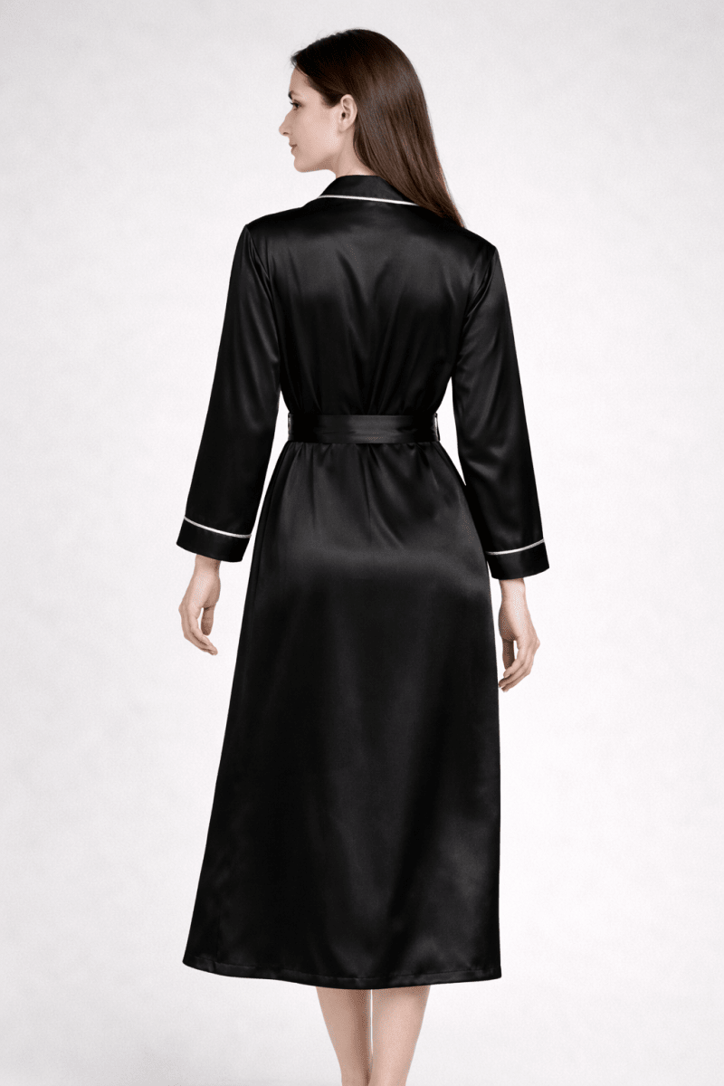 Woman wearing a black silk robe with white trim on a white background