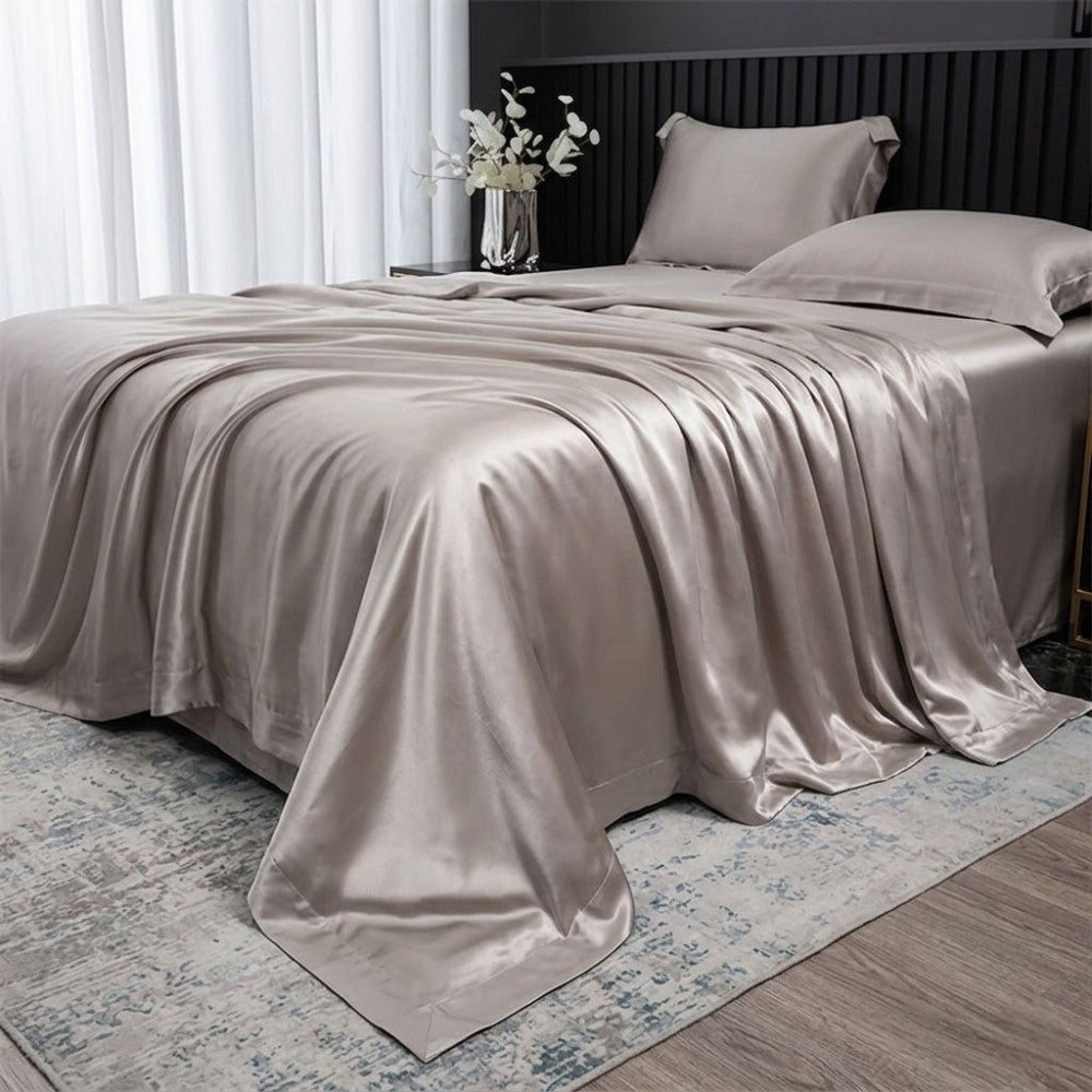 Beige silk sheet set on a bed in a bedroom setting with a vase of flowers.