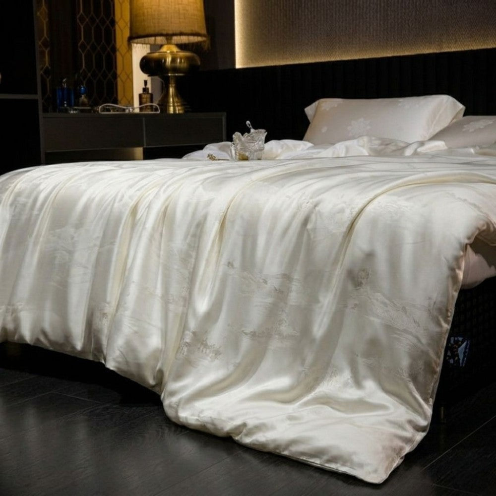 White comforter on a bed in a bedroom setting with a lamp and nightstand.