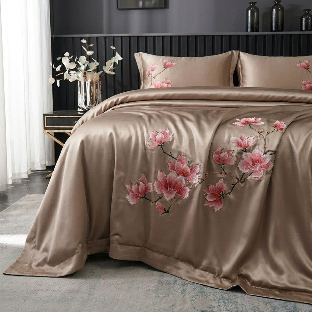 Beige bedspread with pink floral patterns on a bed in a bedroom setting.