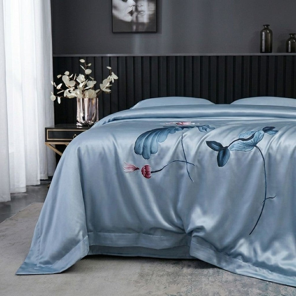Blue floral embroidered bedspread on a bed in a bedroom setting.
