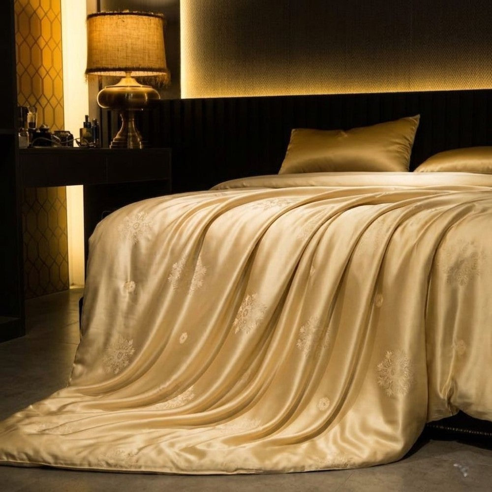 Gold yellow silk duvet cover draped over a bed in a dimly lit bedroom.