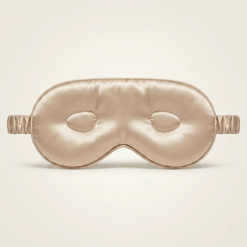 Champagne gold silk sleep mask on a beige background