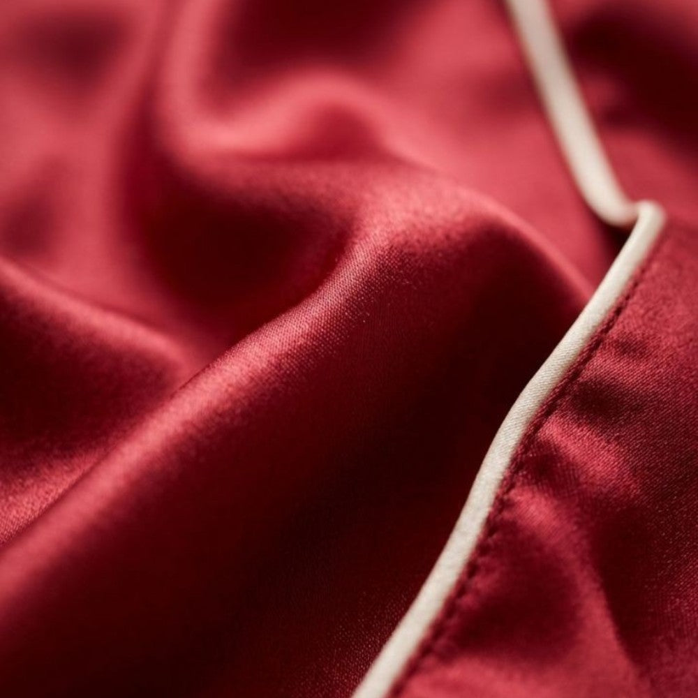 Close-up of red silk fabric with a white seam