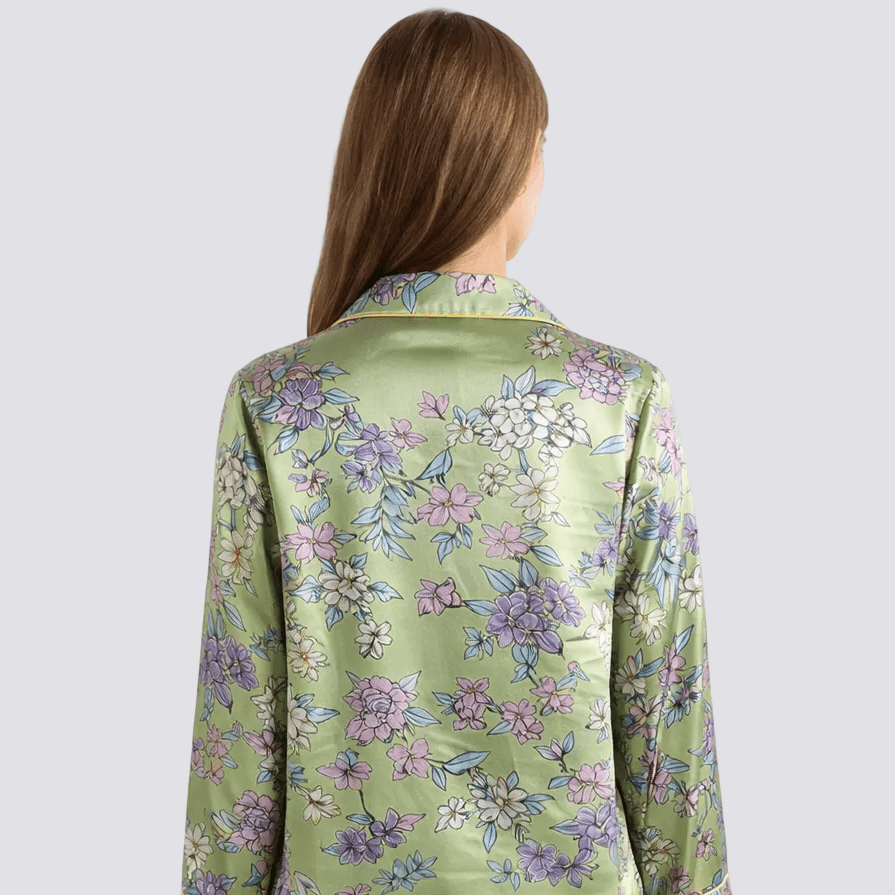 Woman wearing a floral silk pajama top on a white background
