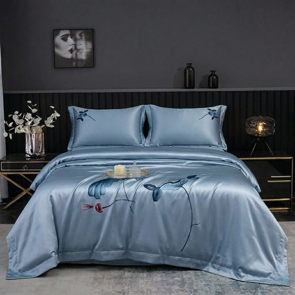 Blue floral embroidered bedding set on a bed in a bedroom setting.