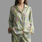 Woman wearing a green silk floral pajama set against a neutral background