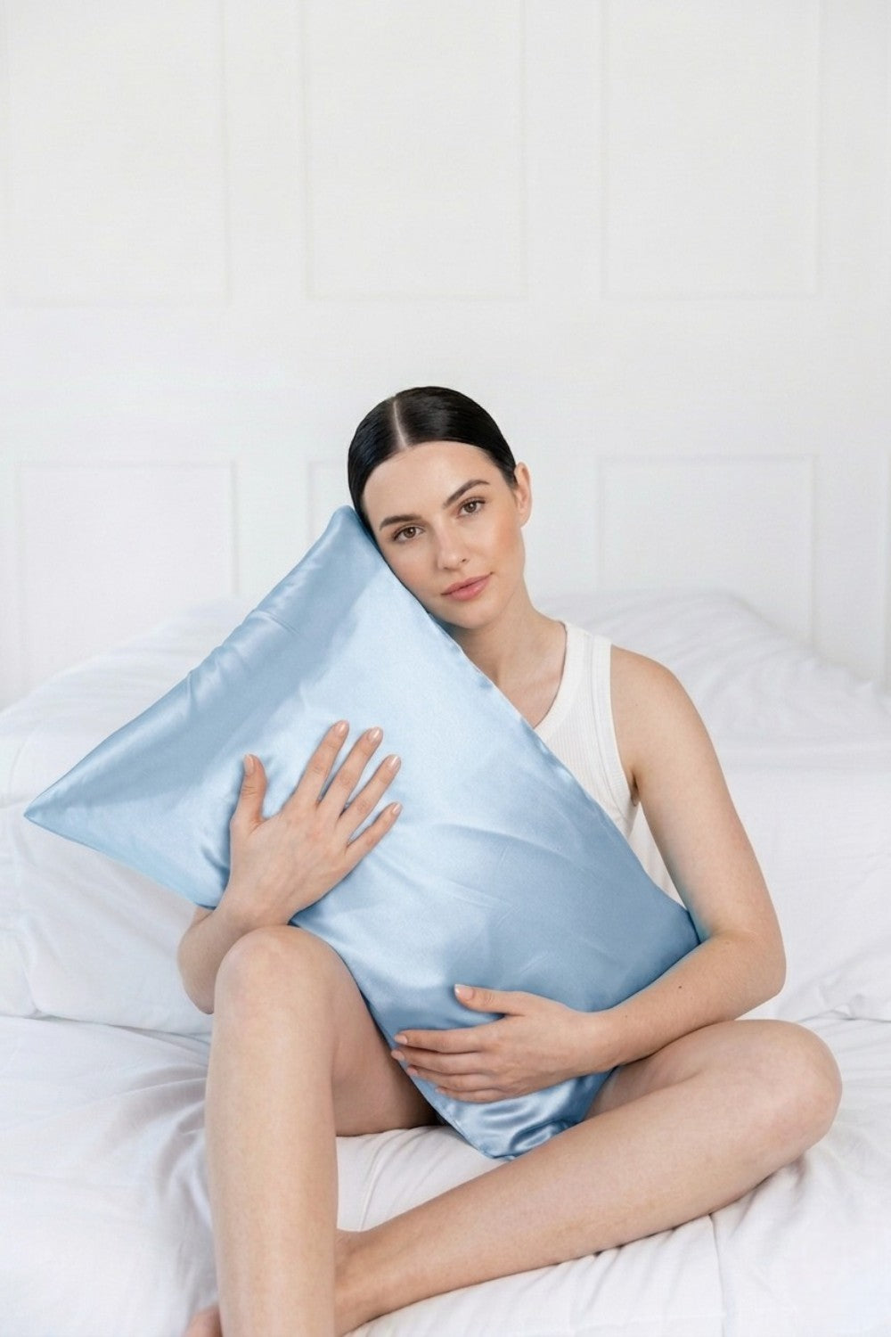 a model leaning on a light blue silk pillowcase