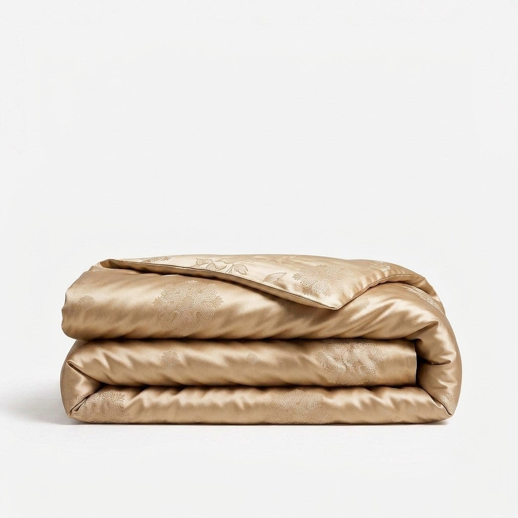 A folded champagne gold silk duvet cover with a subtle damask pattern, displayed on a clean white background.